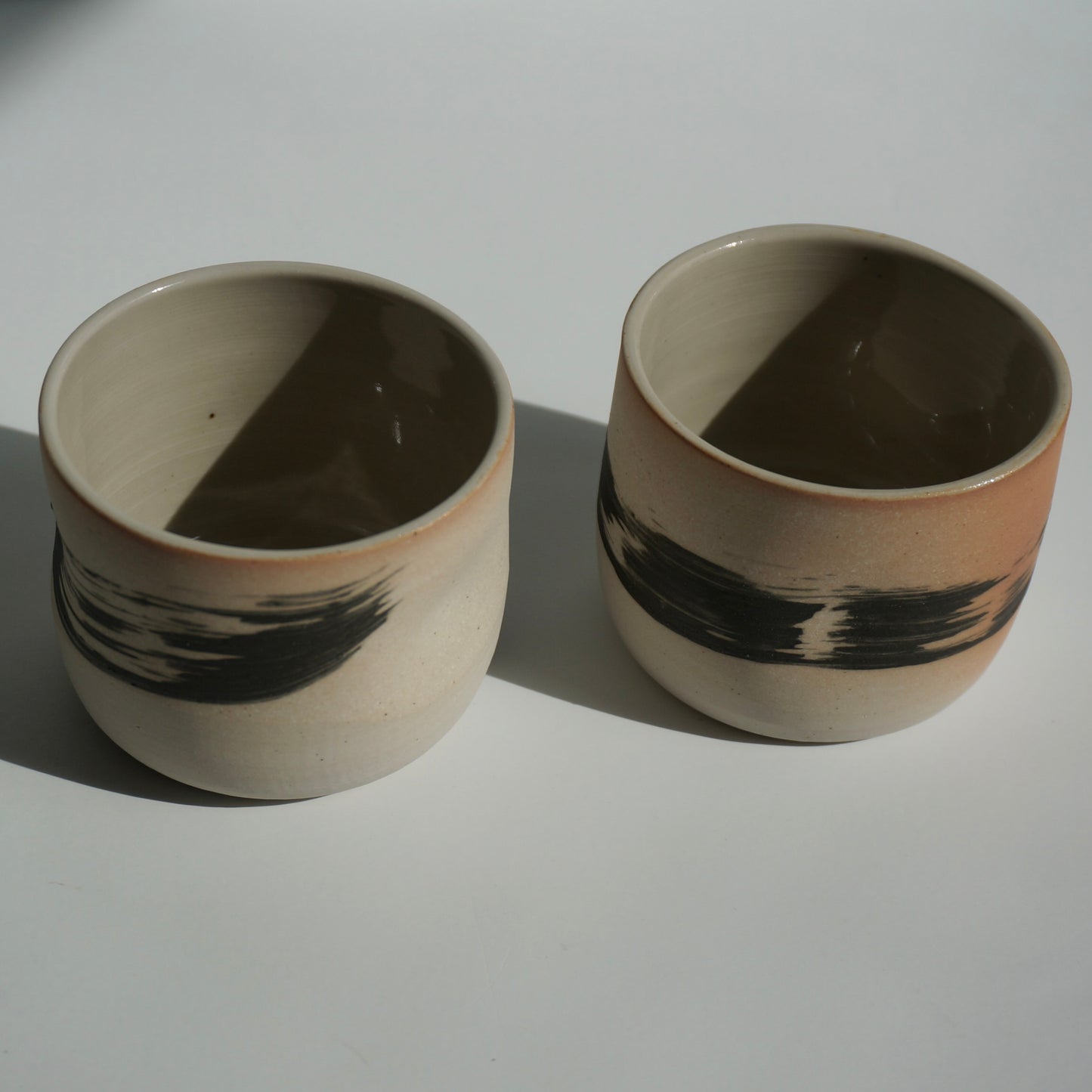 Two handmade ceramic cups with black brushstrokes by Kongji Pottery