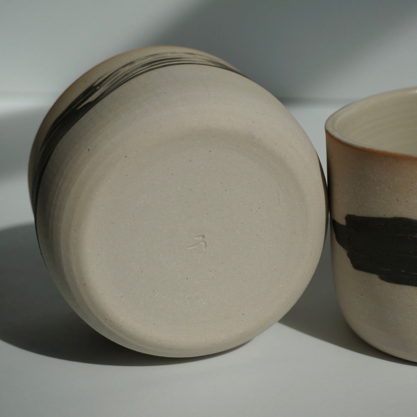 Two handmade ceramic cups with black brushstrokes by Kongji Pottery