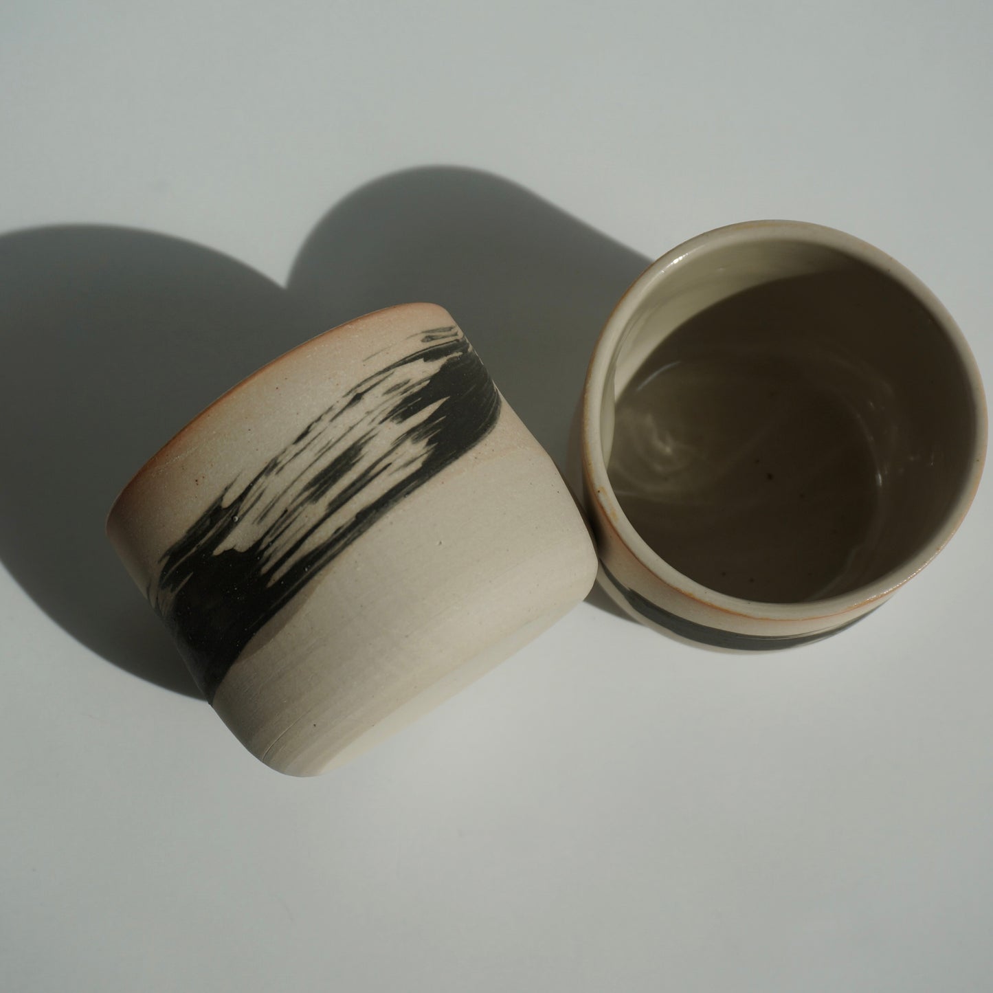 Two handmade ceramic cups with black brushstrokes by Kongji Pottery