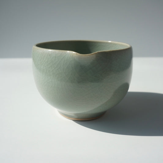 Handmade wheel thrown ceramic spouted matcha bowl in a crackled celadon glaze. Made by Kongji Pottery.