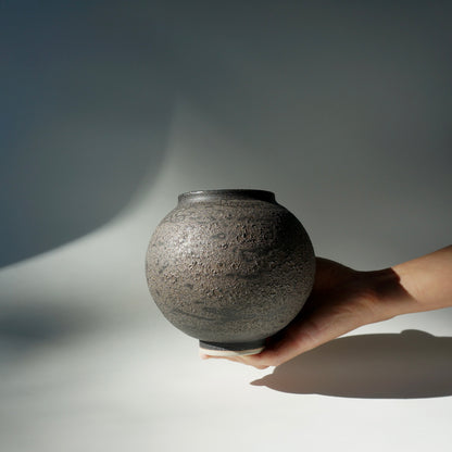 Hand holding a textured ceramic handmade moon jar by Kongji Pottery