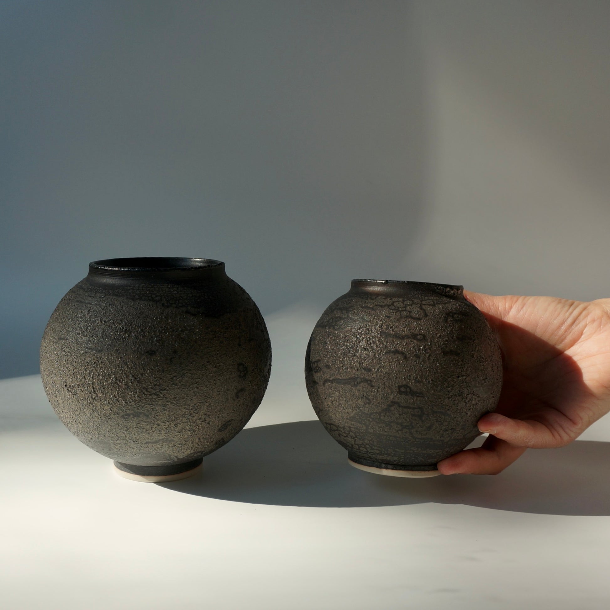 Two black textured handmade ceramic moon jars by Kongji Pottery