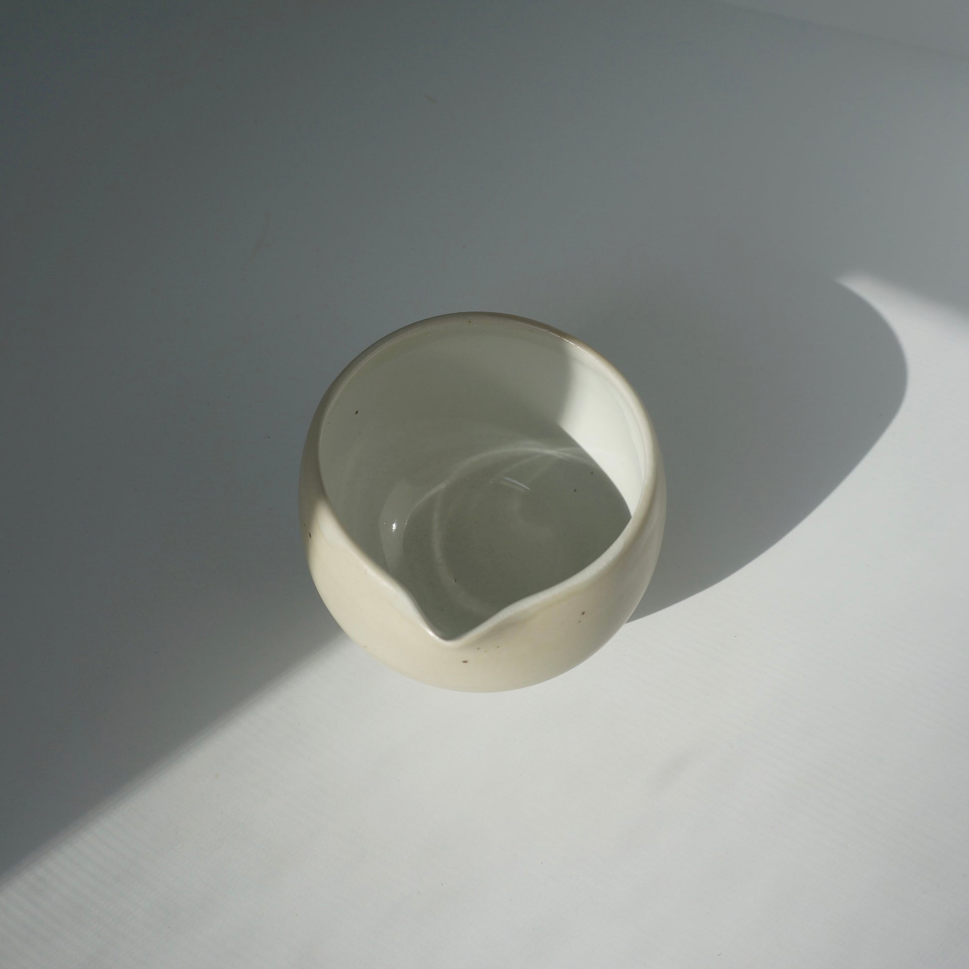 Handmade wheel thrown ceramic spouted matcha bowl in matte and glossy white. Made by Kongji Pottery.