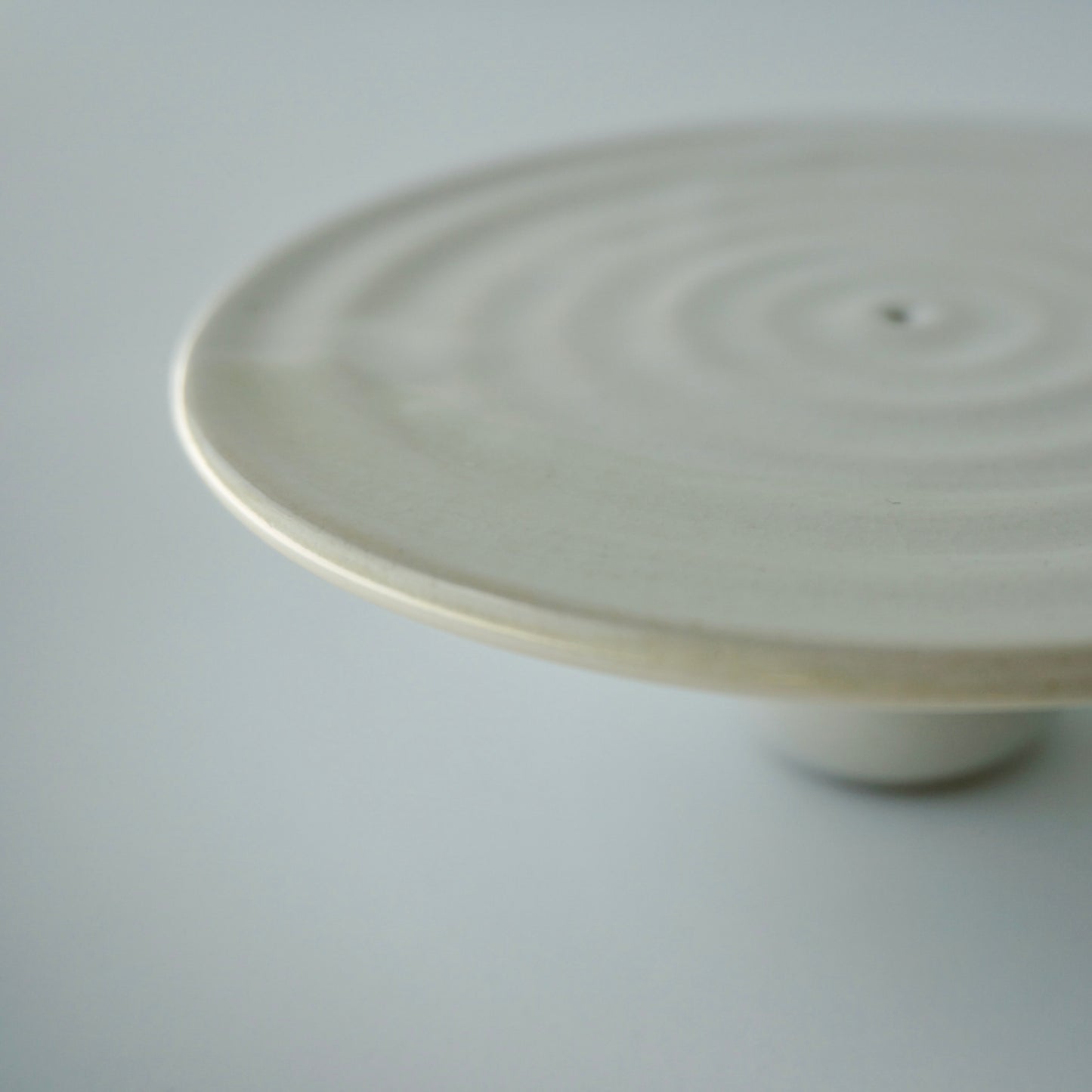 Handmade ceramic zen incense holder by Kongji Pottery. Pedestal form glazed in glossy white with a hint of light green brushed on the edge.