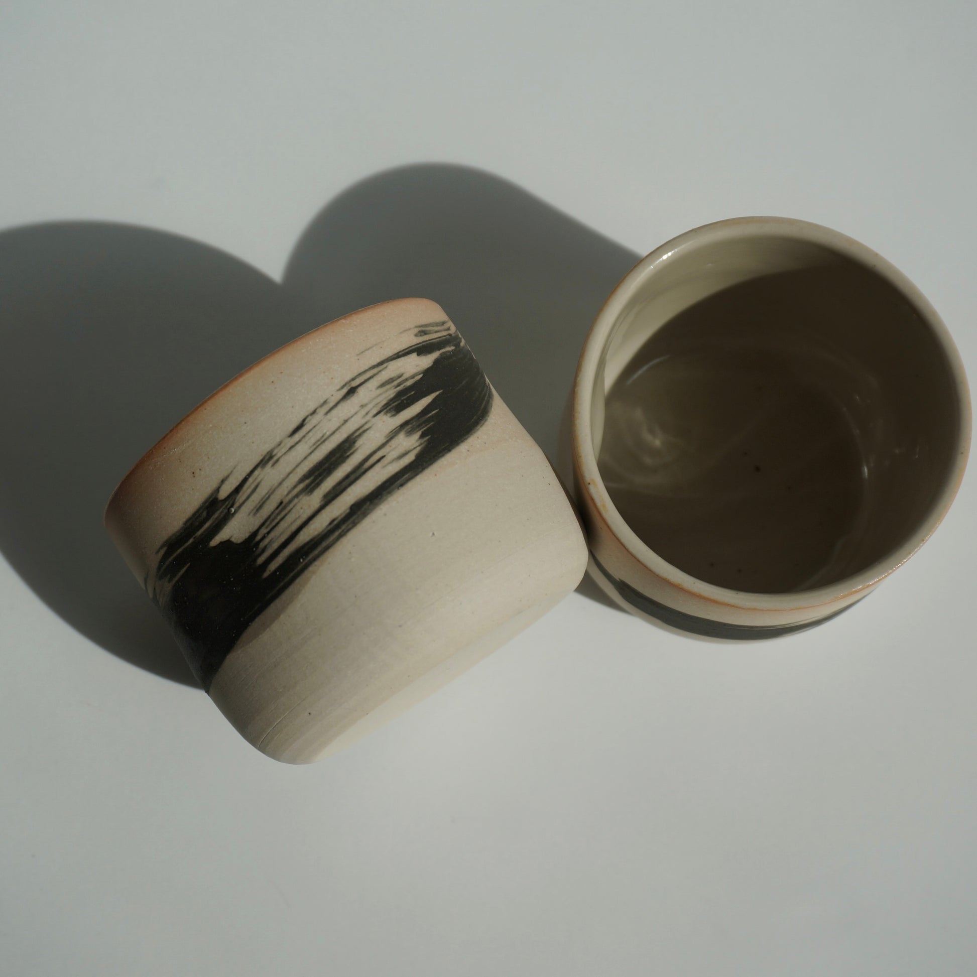 Two handmade ceramic cups with black brushstrokes by Kongji Pottery